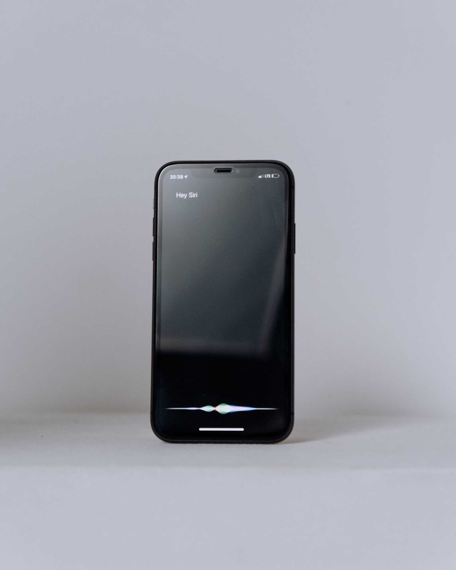 Smartphone running a voice assistant on a plain grey surface
